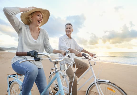 a man and woman riding bikes on the beach