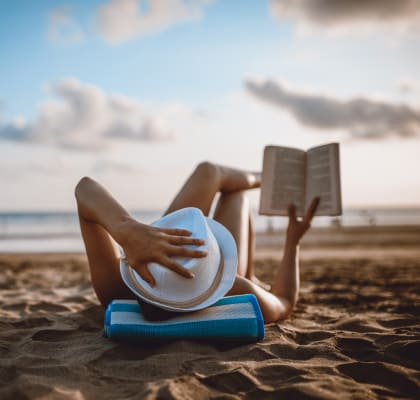 woman laying on the beach reading a book